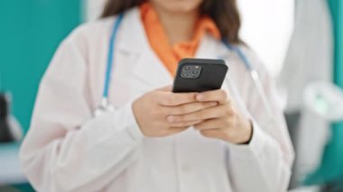 Klinikte akıllı telefon kullanan genç, güzel İspanyol kadın doktor.
