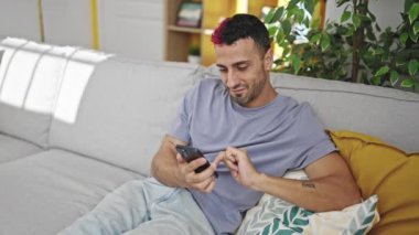 İki erkek akıllı telefon kullanıp evde kahve içiyorlar.