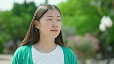 Parkta hapşıran genç Çinli bir kadın.