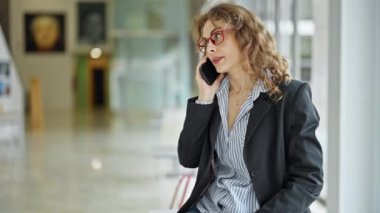 Genç iş kadını akıllı telefondan konuşuyor ofiste kahve içiyor.