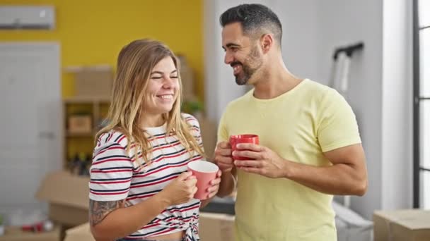 新しい家でコーヒーを飲みながら一緒に立っている男女カップル — ストック動画