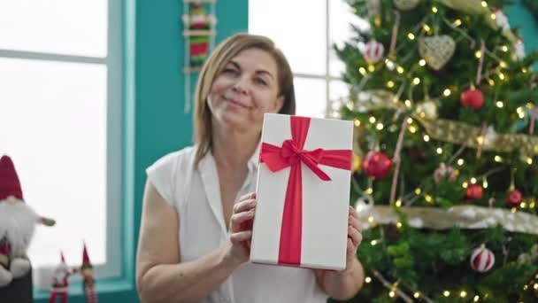 Middelbare Leeftijd Spaanse Vrouw Glimlachend Zelfverzekerd Houden Kerstcadeau Thuis — Stockvideo