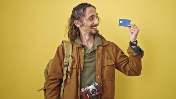 若いヒスパニック男性観光客は 単離された黄色の背景の上に勝者のジェスチャーでクレジットカードを保持しています — ストック動画