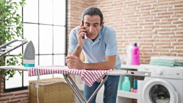 Hombre Mediana Edad Hablando Teléfono Inteligente Apoyado Máquina Planchar Sala — Vídeos de Stock