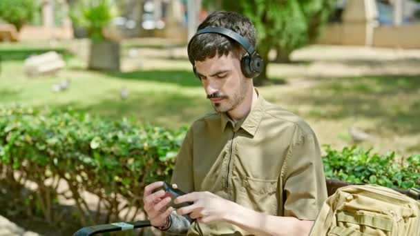 Fiatal Spanyol Férfi Zenét Hallgat Lazán Padon Parkban — Stock videók