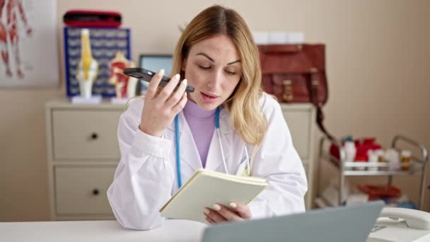 年轻美丽的惊慌失措的女医生在诊所用智能手机读书机发送语音讯息 — 图库视频影像
