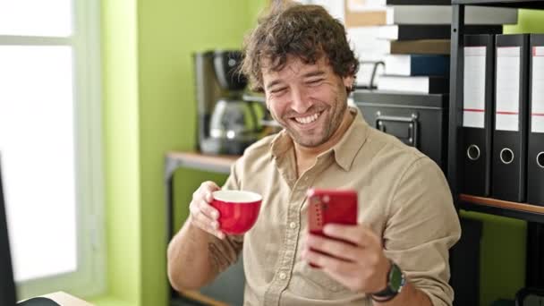 Νέος Ισπανόφωνος Επιχειρηματίας Χρησιμοποιώντας Smartphone Πίνοντας Καφέ Στο Γραφείο — Αρχείο Βίντεο