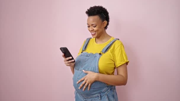 Mujer Embarazada Joven Usando Teléfono Inteligente Sonriendo Sobre Fondo Rosa — Vídeo de stock