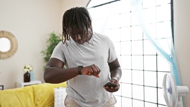African American Man Using Smartphone Looking Watch Home — 图库视频影像