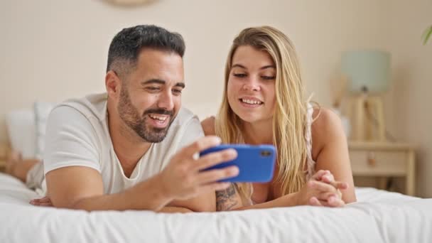 寝室で話すスマートフォンを使ってベッドに横たわる男女カップル — ストック動画
