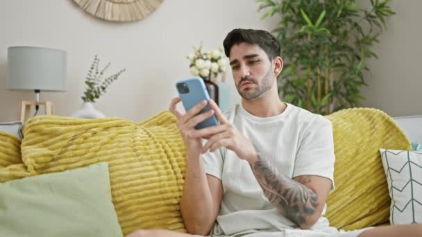 Jovem Hispânico Usando Smartphone Sentado Sofá Com Expressão Triste Casa — Vídeo de Stock