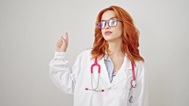 Joven Pelirroja Doctora Sonriendo Señalando Hacia Lado Sobre Fondo Blanco — Vídeos de Stock