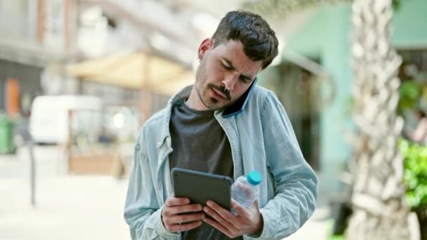 Νεαρός Ισπανός Που Χρησιμοποιεί Touchpad Μιλώντας Smartphone Κρατώντας Ένα Μπουκάλι — Αρχείο Βίντεο