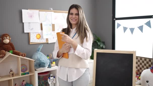Mladá Krásná Hispánská Žena Předškolní Učitel Usmívá Sebevědomě Drží Knihu — Stock video