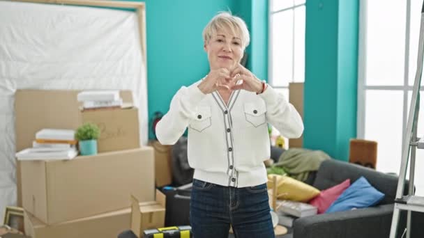 Medelålders Blond Kvinna Gör Hjärtgest Nytt Hem — Stockvideo