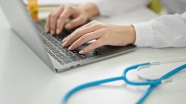 Genç Çinli kadın doktor klinikte çalışırken dizüstü bilgisayar kullanıyor.