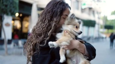 Köpeğiyle gülümseyen, sokakta kendine güvenen genç İspanyol kadın.