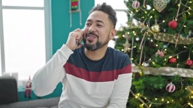 Genç latin adam akıllı telefondan Noel 'i evde kutluyor.