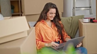 Genç, güzel İspanyol bir kadın yeni evindeki kanepede otururken görüntülü konuşma yapıyor.