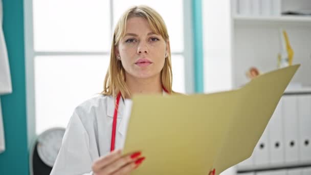 Young Blonde Woman Doctor Reading Medical Report Saying Head Clinic — Stock Video