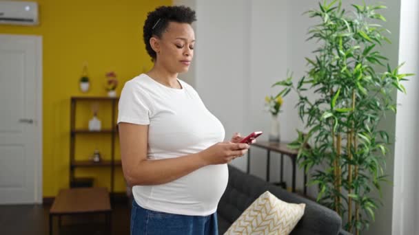 Junge Schwangere Lächelt Mit Smartphone Hause — Stockvideo