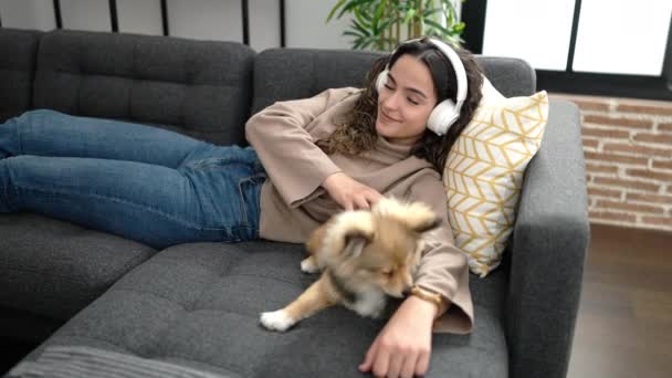 Молодая Латиноамериканка Собакой Слушает Музыку Лежащую Дома Диване — стоковое видео