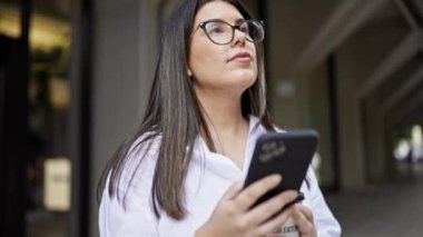 Madrid sokaklarında akıllı telefon kullanarak gülümseyen güzel İspanyol kadın.