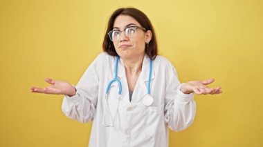 Genç, güzel İspanyol kadın doktor, izole edilmiş sarı arka planda hiçbir şeyden habersiz duruyor.