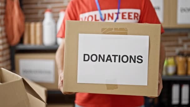 Joven Hombre Hispano Voluntario Sosteniendo Donaciones Caja Cartón Centro Caridad — Vídeo de stock