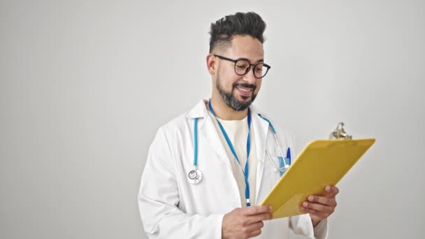 年轻的拉丁男医生正在阅读医学报告 在孤立的白人背景下做着大拇指向上的手势 — 图库视频影像