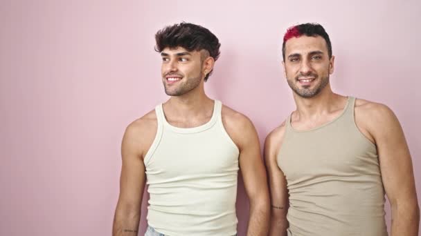 两个男人站在一起 脸上带着惊讶的表情 指着旁边孤立的粉色背景 — 图库视频影像