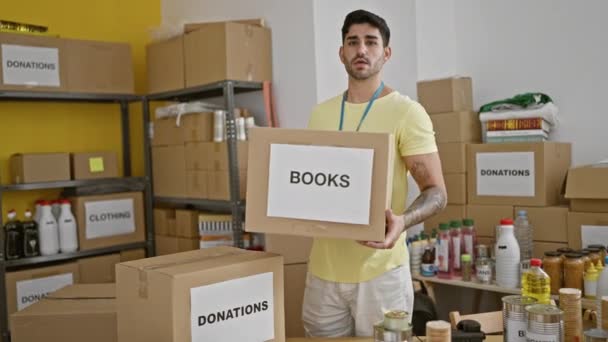 Jovem Hispânico Homem Voluntário Segurando Livros Pacote Para Doar Sorrindo — Vídeo de Stock