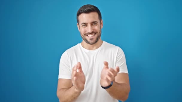 Νεαρός Ισπανόφωνος Χαμογελάει Αυτοπεποίθηση Χειροκροτώντας Απομονωμένο Μπλε Φόντο — Αρχείο Βίντεο