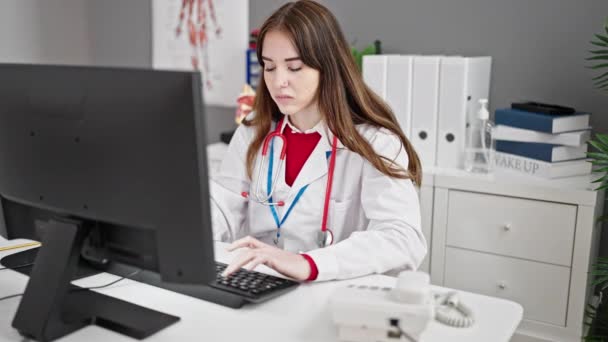 若いヒスパニック女性医師は 診療所で電話で話すコンピュータを使用しています — ストック動画