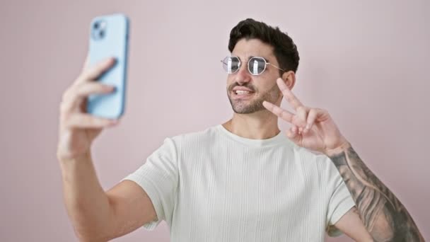 Молодой Латиноамериканец Улыбается Уверенно Делая Селфи Смартфоне Изолированном Розовом Фоне — стоковое видео