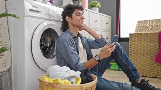 Çamaşır Odasında Çamaşır Makinesi Bekleyen Akıllı Telefon Kullanan Genç Bir — Stok video