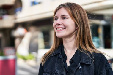 Young blonde woman smiling confident looking to the side at street