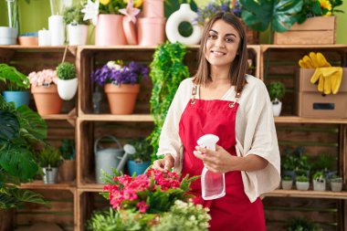 Çiçekçide difüzör sulama bitkisi kullanan güzel İspanyol bir çiçekçi kadın.