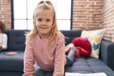 Evdeki kanepede uzanmış gülümseyen sevimli sarışın kız.