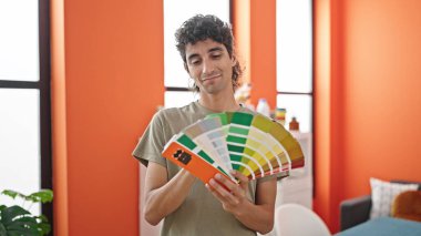 Genç İspanyol adam yemek odasında renk testi yaparken gülümsüyor.