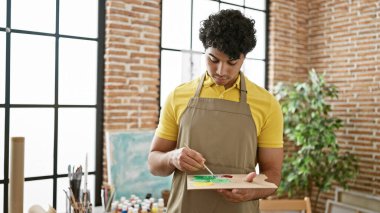 Sanat stüdyosunda renkleri karıştıran genç Latin bir sanatçı.