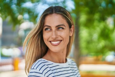 Young blonde woman smiling confident looking to the side at park