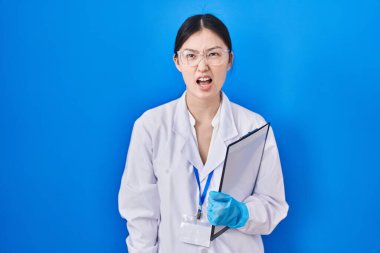 Bilim adamlarının laboratuvarında çalışan Çinli genç bir kadın kızgın ve kızgın bağırıyor öfkeyle bağırıyor. öfke ve agresif konsept. 