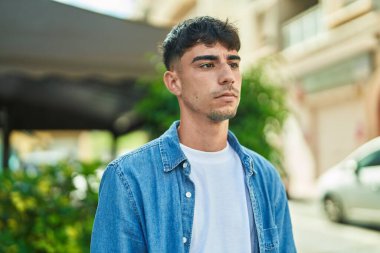 Latin kökenli genç adam ciddi bir ifadeyle sokağa bakıyor.