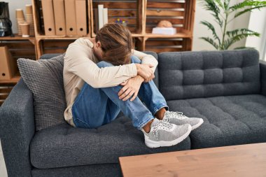 Young caucasian man patient stressed sitting on sofa at psychology clinic
