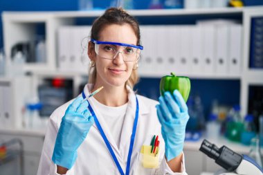 Bilim adamlarının laboratuvarında çalışan genç İspanyol kadın. Yüzünde ciddi bir ifadeyle rahatlamış bir şekilde sebzelerle çalışıyor. Basit ve doğal bir şekilde kameraya bakıyorsun.. 