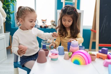 Anaokulundaki masada oturan inşaat bloklarıyla oynayan sevimli kızlar.