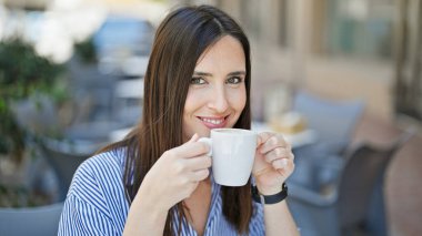 Kahve dükkanının terasında kahve içen genç, güzel İspanyol kadın.