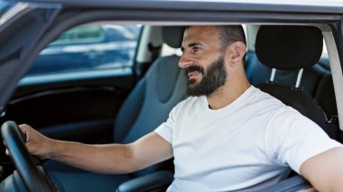 Young hispanic man smiling confident driving car at street