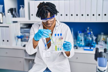 Laboratuvarda test tüpleri tutan Afrikalı Amerikalı bilim adamı.